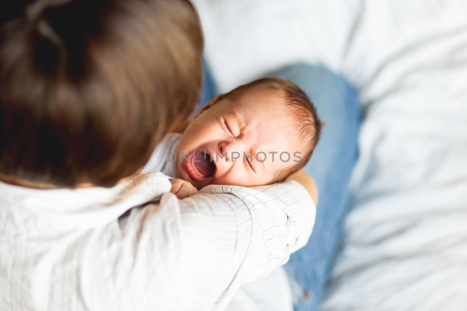 Woman holding a crying child. Mother comforts her little son or daughter.