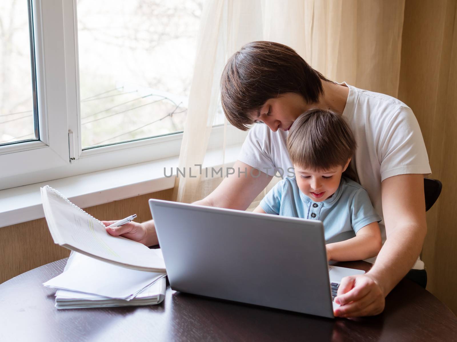 Self-isolation because of coronavirus outbreak. Man is remote working with his little son on self quarantine. Lockdown.