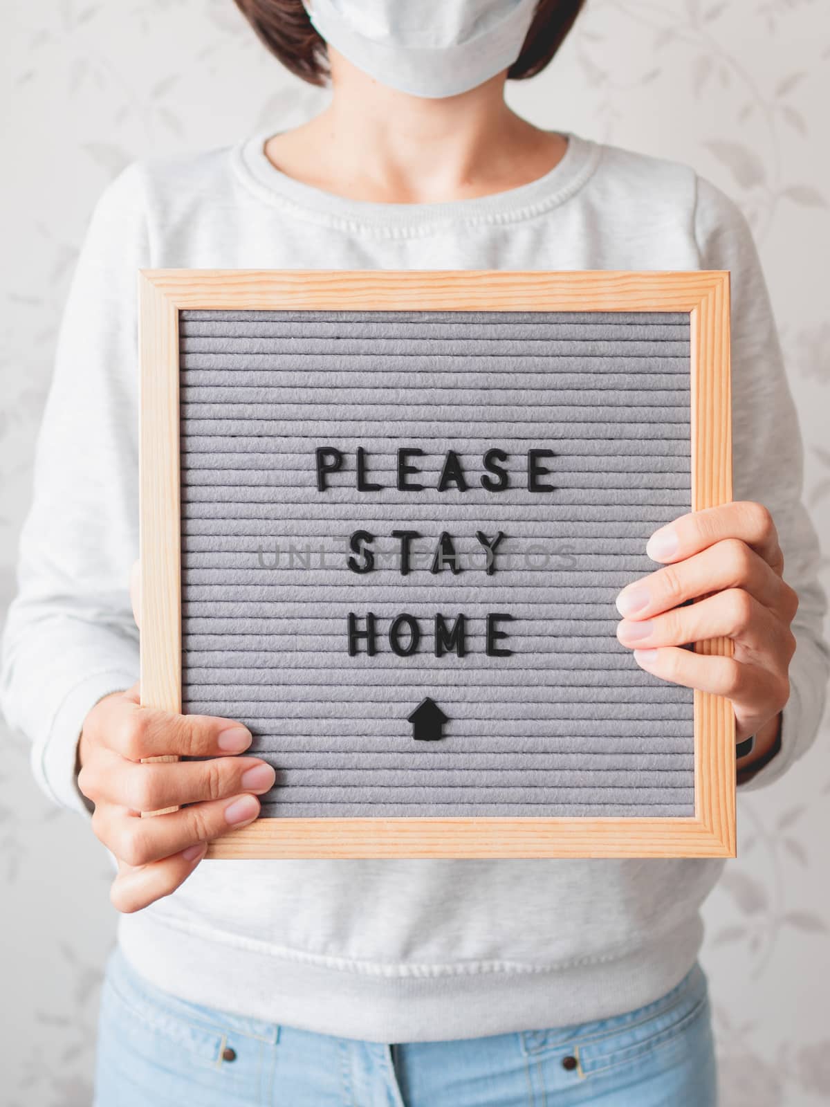 Woman in medical mask with letter board. Phrase PLEASE STAY HOME. Quarantine because of coronavirus COVID19. Self-isolation at home.