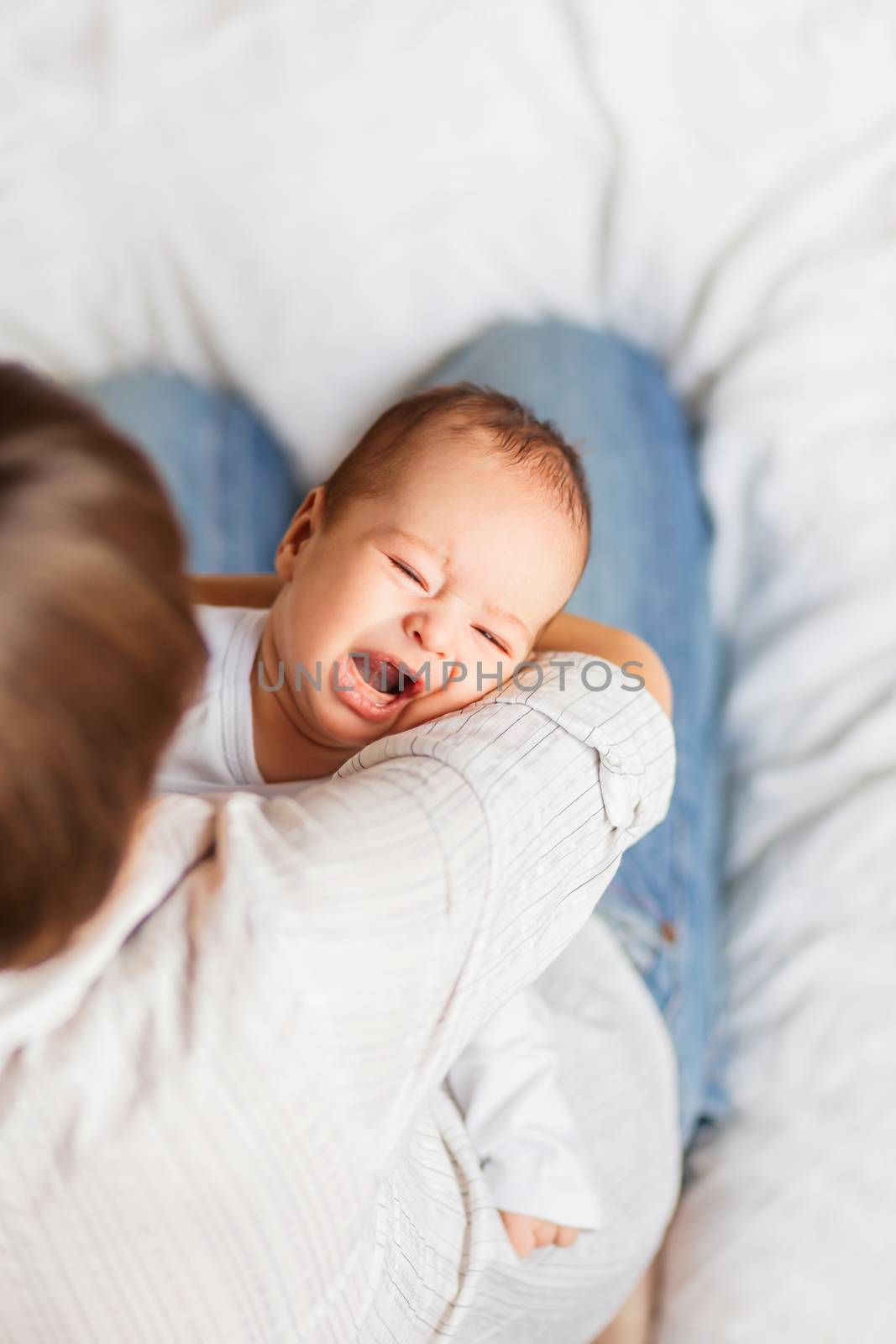 Woman holding a crying child. Mother comforts her little son or daughter. .