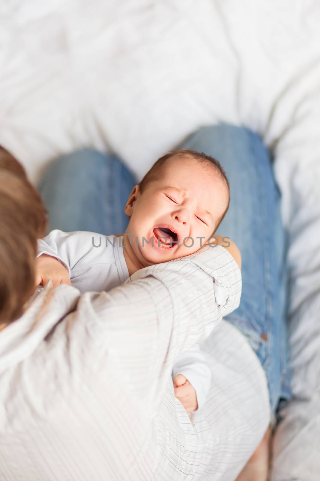 Woman holding a crying child. Mother comforts her little son or daughter.