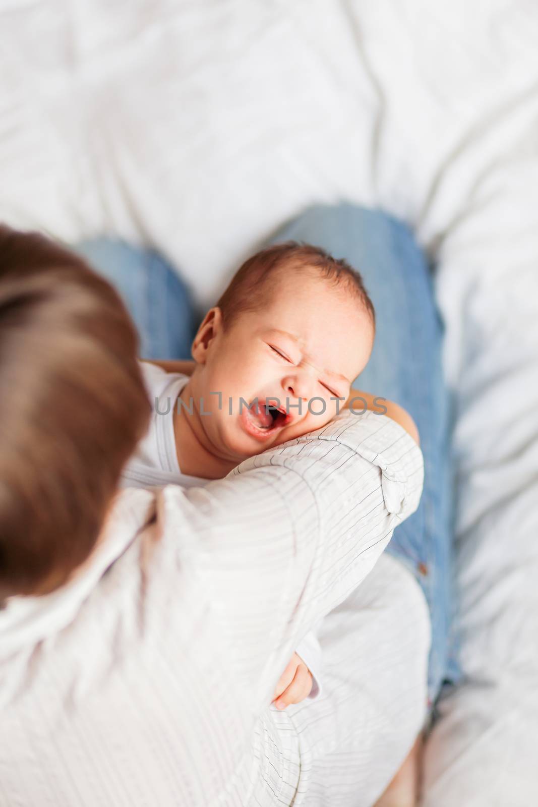 Woman holding a crying baby. Mother comforts her little son or daughter.