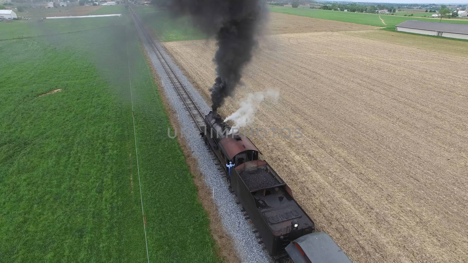 Aerial View of a Steam Passenger Train Puffing Smoke in Amish Countryside on a Sunny Spring Day