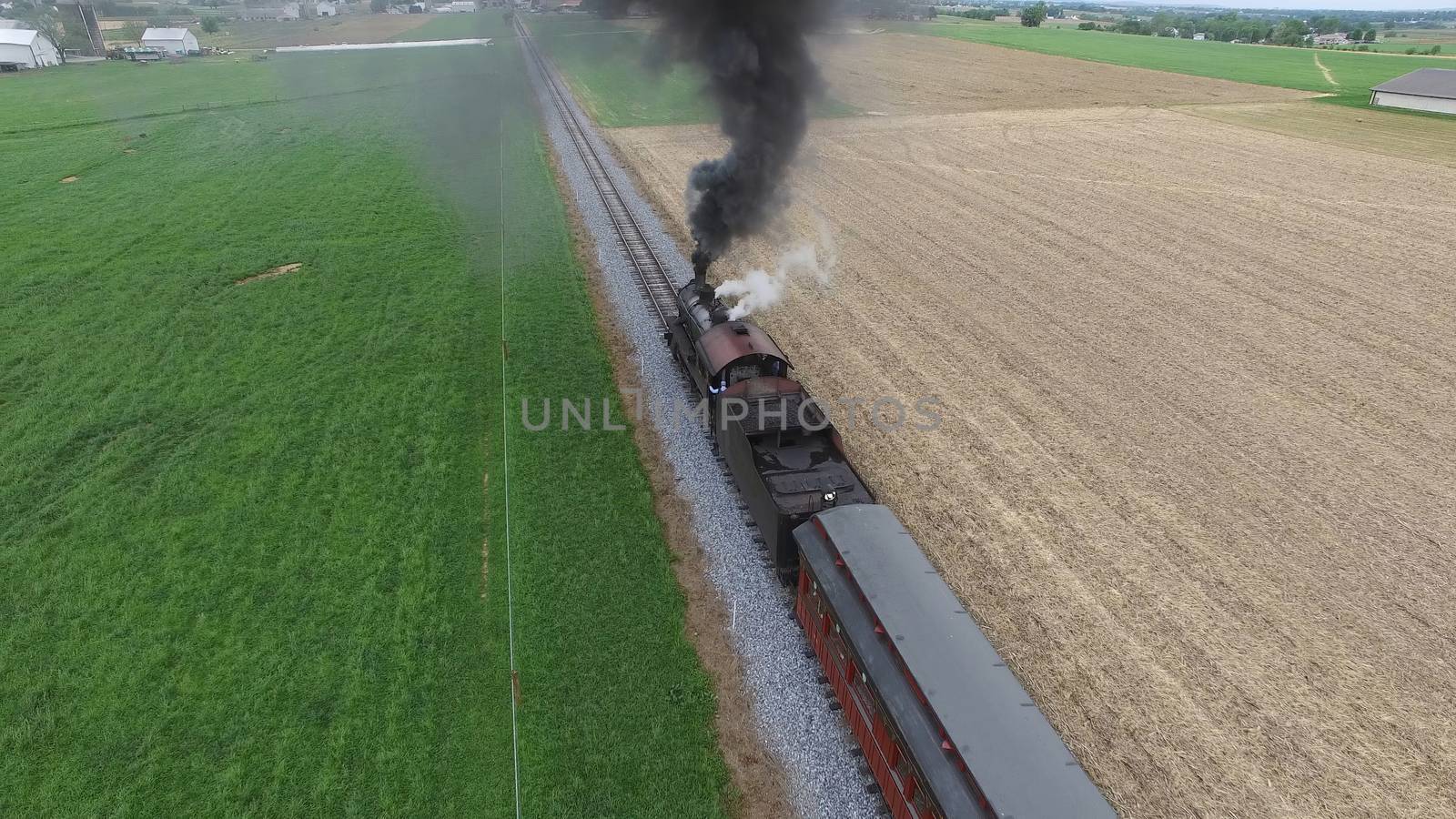 Aerial View of a Steam Passenger Train Puffing Smoke in Amish Countryside on a Sunny Spring Day