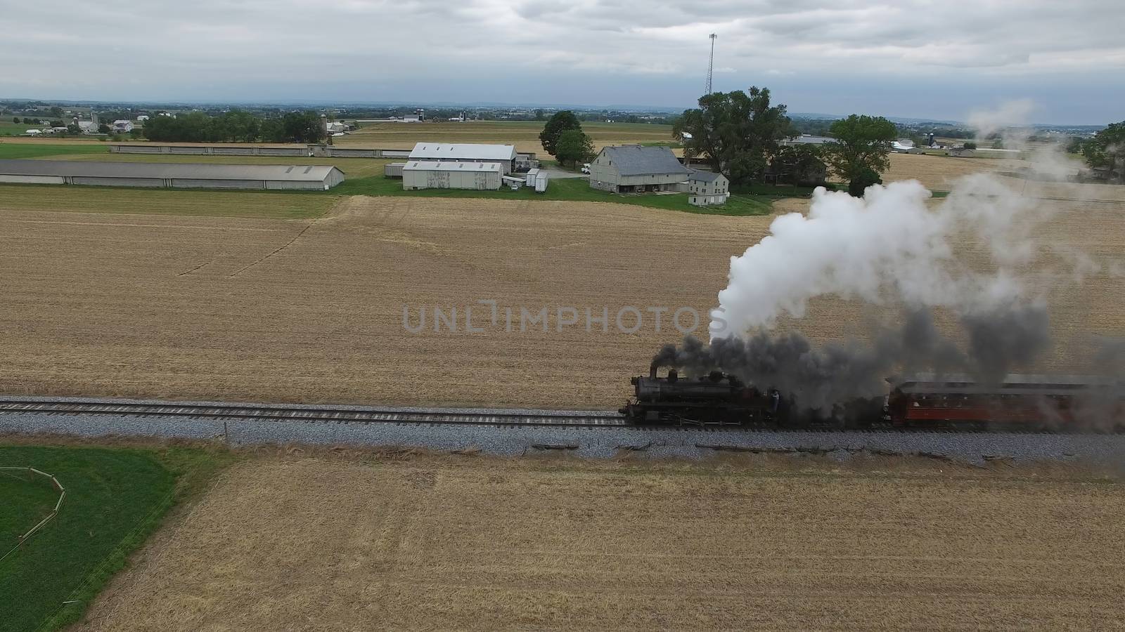 Aerial View of a Steam Passenger Train Puffing Smoke in Amish Countryside on a Sunny Spring Day