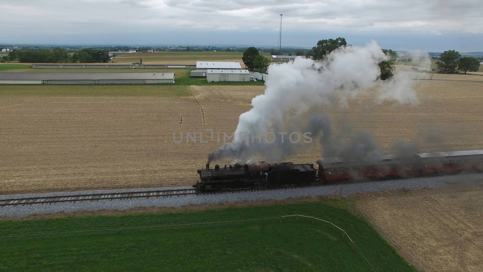 Aerial View of a Steam Passenger Train Puffing Smoke in Amish Countryside on a Sunny Spring Day