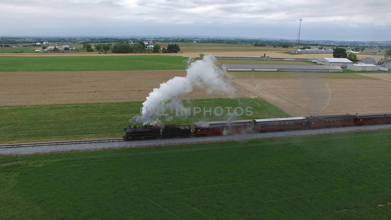 Aerial View of a Steam Passenger Train Puffing Smoke in Amish Countryside on a Sunny Spring Day