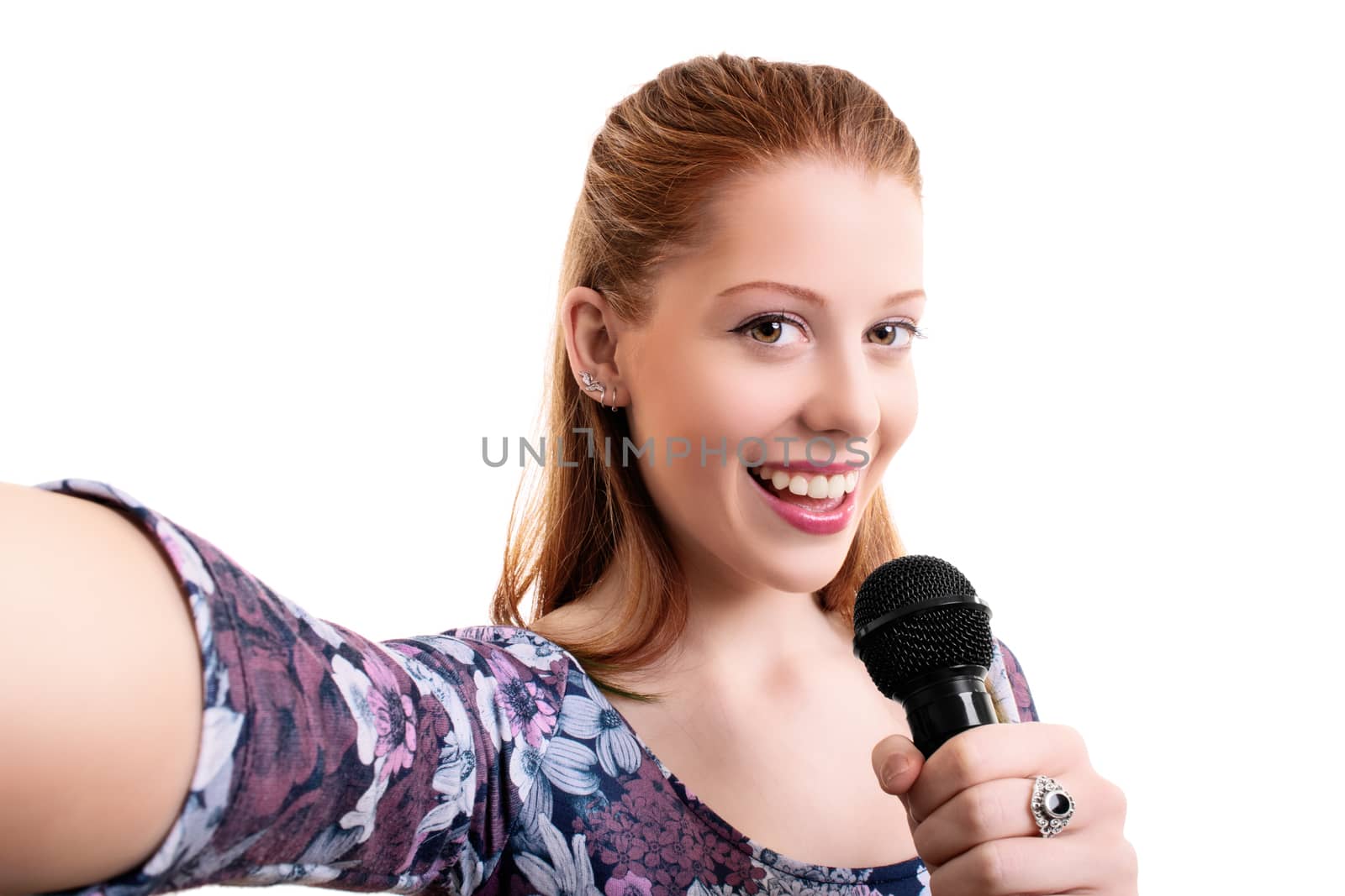 Beautiful young girl holding a microphone and taking a selfie, isolated on white background. Lifestyle, happiness, and social concept. Fashionable girl with a microphone singing and taking a selfie.