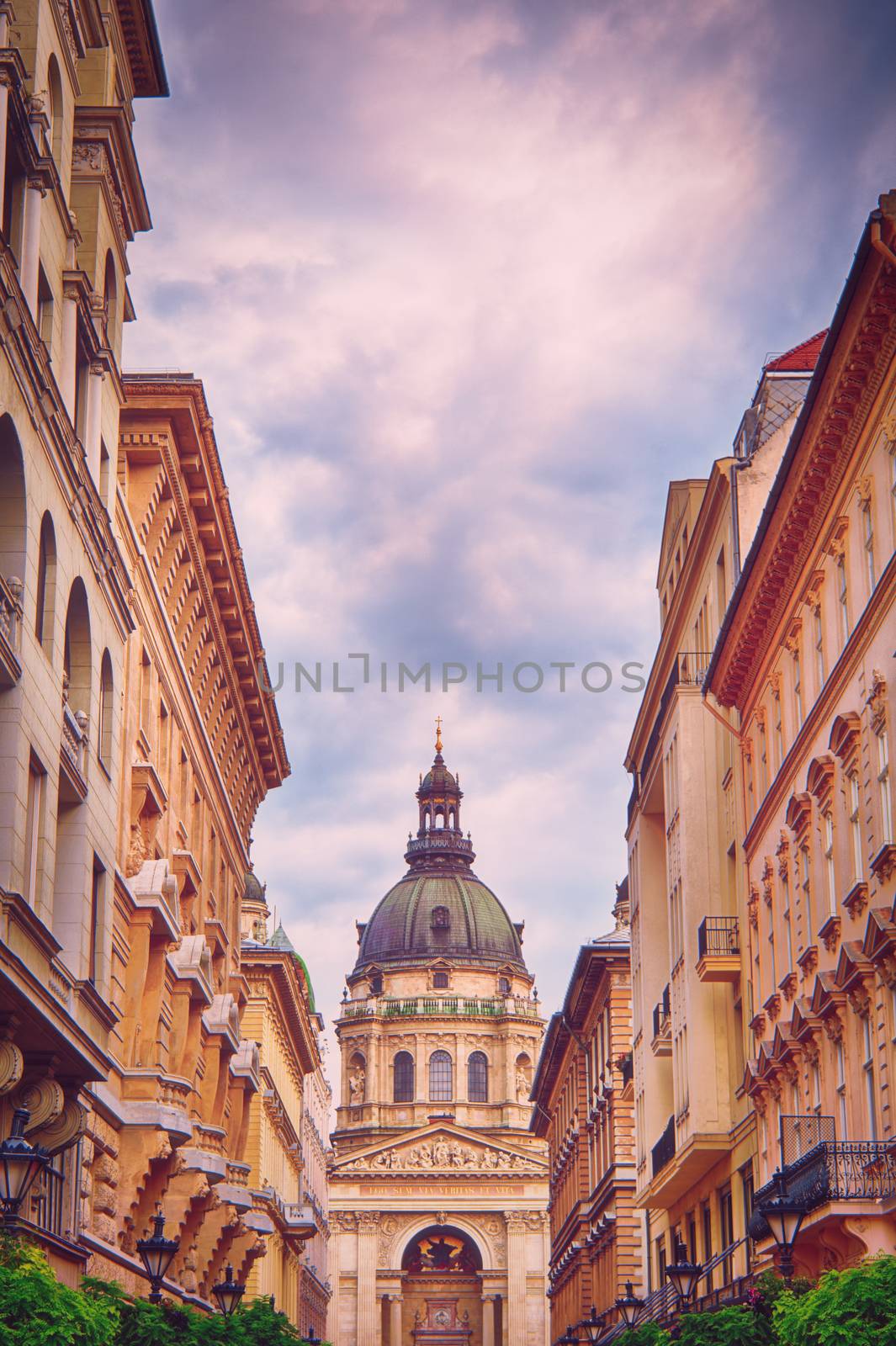 St. Stephen's Basilica in Budapest on a beautiful day seen from the tourist walking street through the buildings.