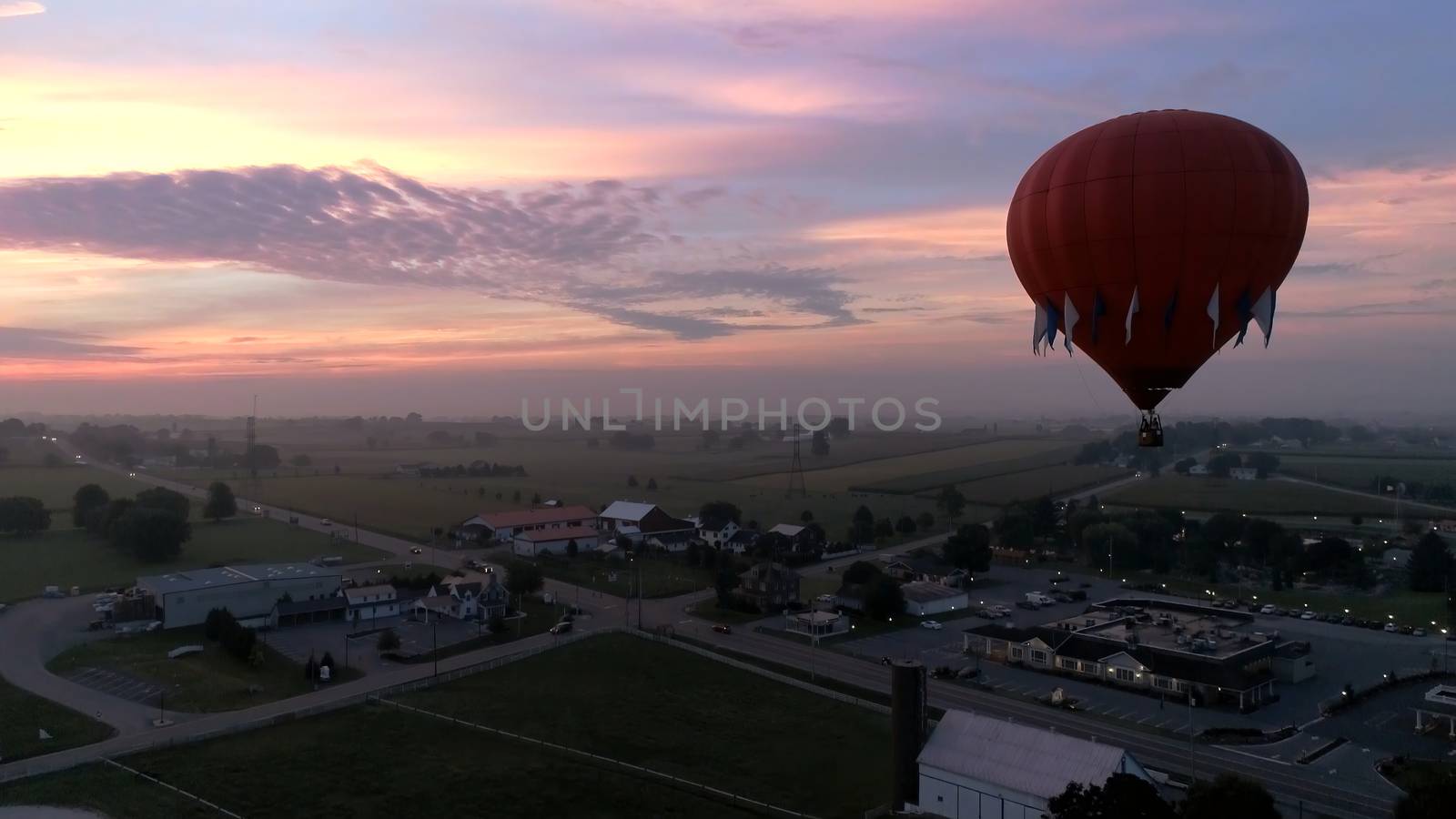 Aerial View of Sunrise with Hot air Balloons Taking Off with Glow as Seen by a Drone