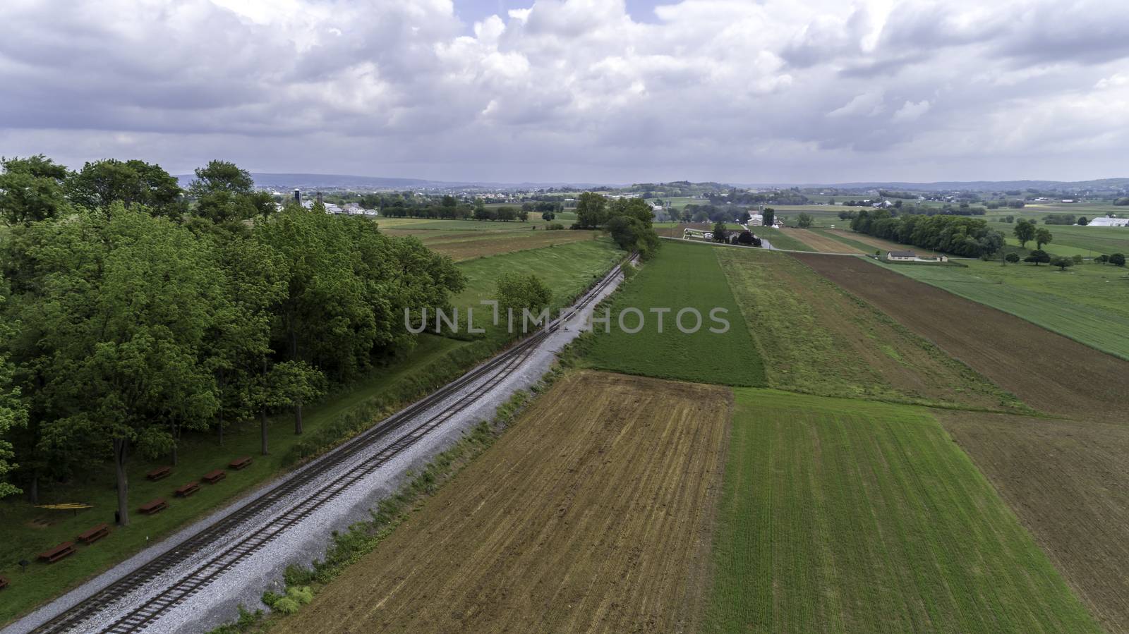 Aerial View of a Steam Passenger Train Puffing Smoke in Amish Countryside on a Sunny Spring Day