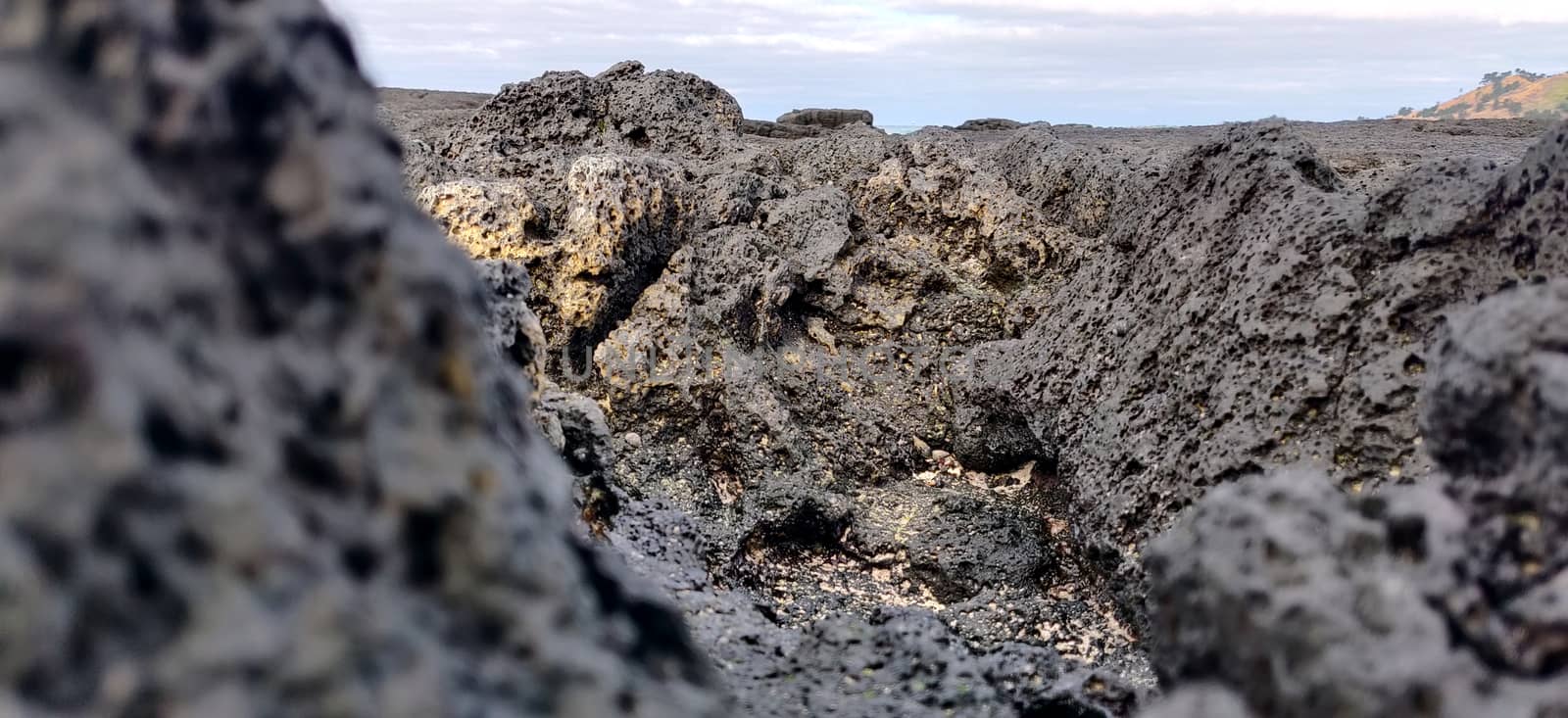 Macro shot of volcanic black rock and sky on the hyeopjae beach while in vacation in jeju island, south korea