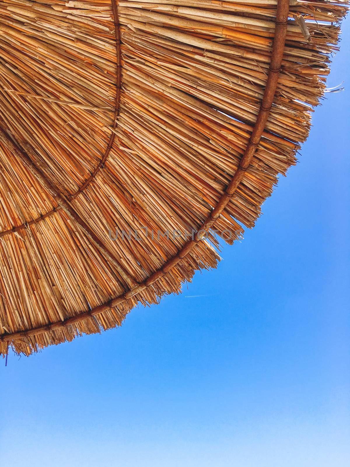 Bottom view of straw beach umbrella on clear blue sky background. Symbol of vacation, rest and relaxation. Kemer, Turkey.
