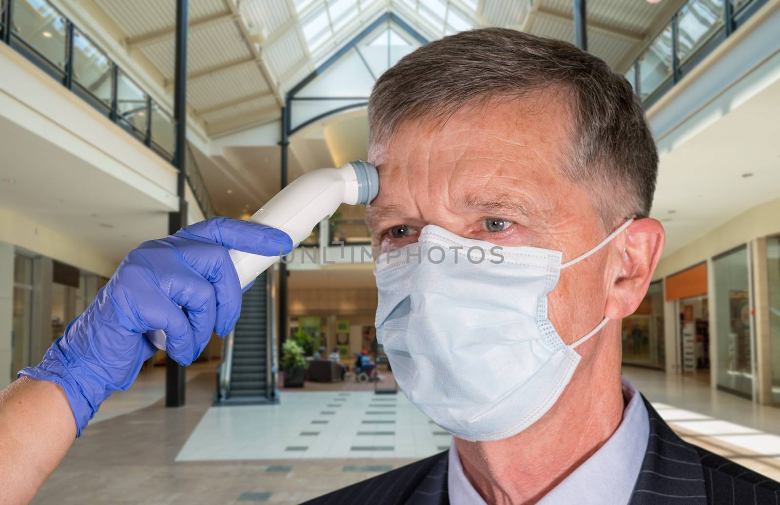 Mockup of shopping mall with senior adult wearing mask having a fever or temperature test taken to check coronavirus status