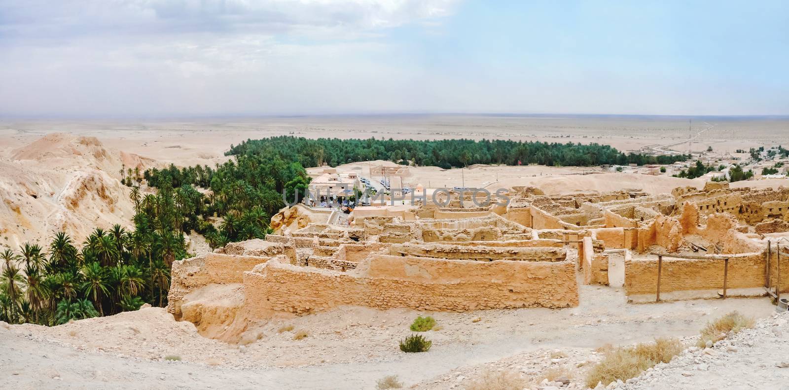 Tourists in oasis Chebika, famous landmark in Sahara desert. Ancient ruines of berbers town. by aksenovko