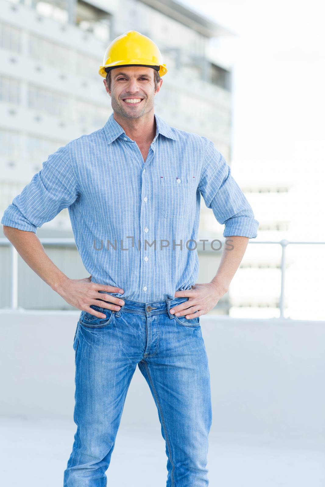 Happy male architect with hands on hips by Wavebreakmedia
