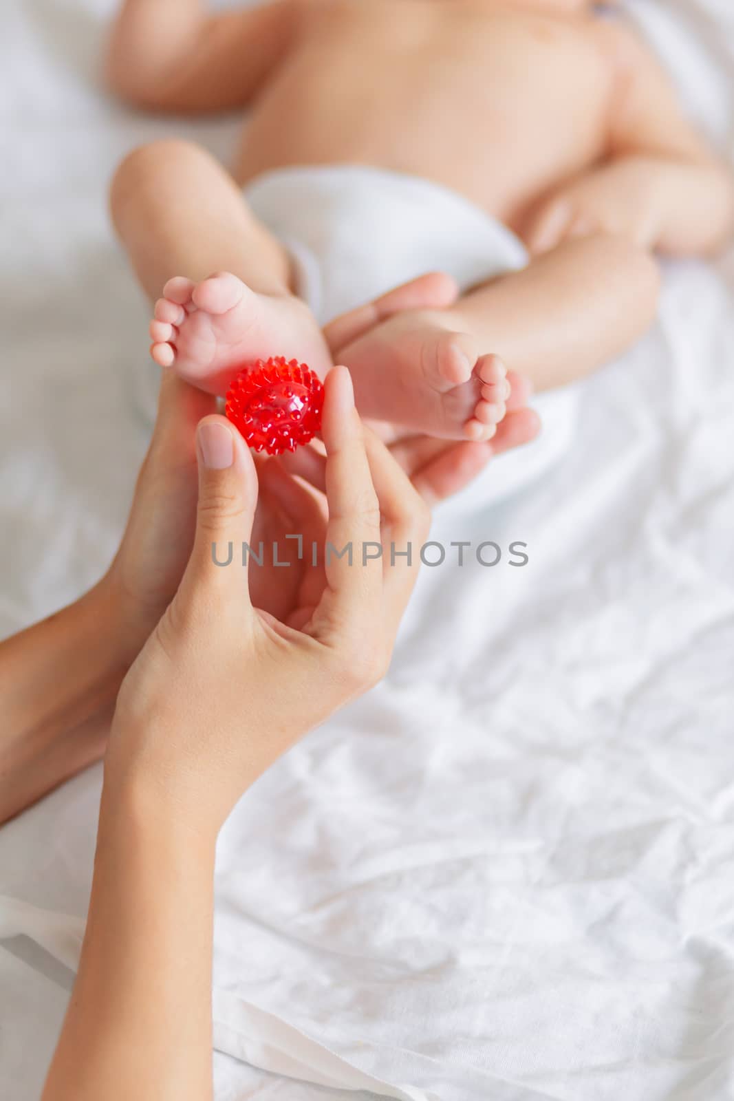 Mother holds newborn baby's feet. Tiny fingers and red massage b by aksenovko