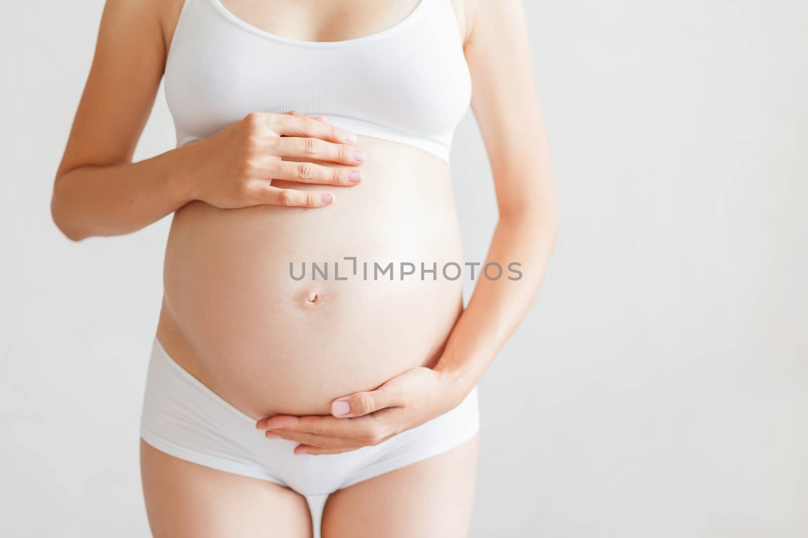 Pregnant woman in white underwear. Young woman expecting a baby.