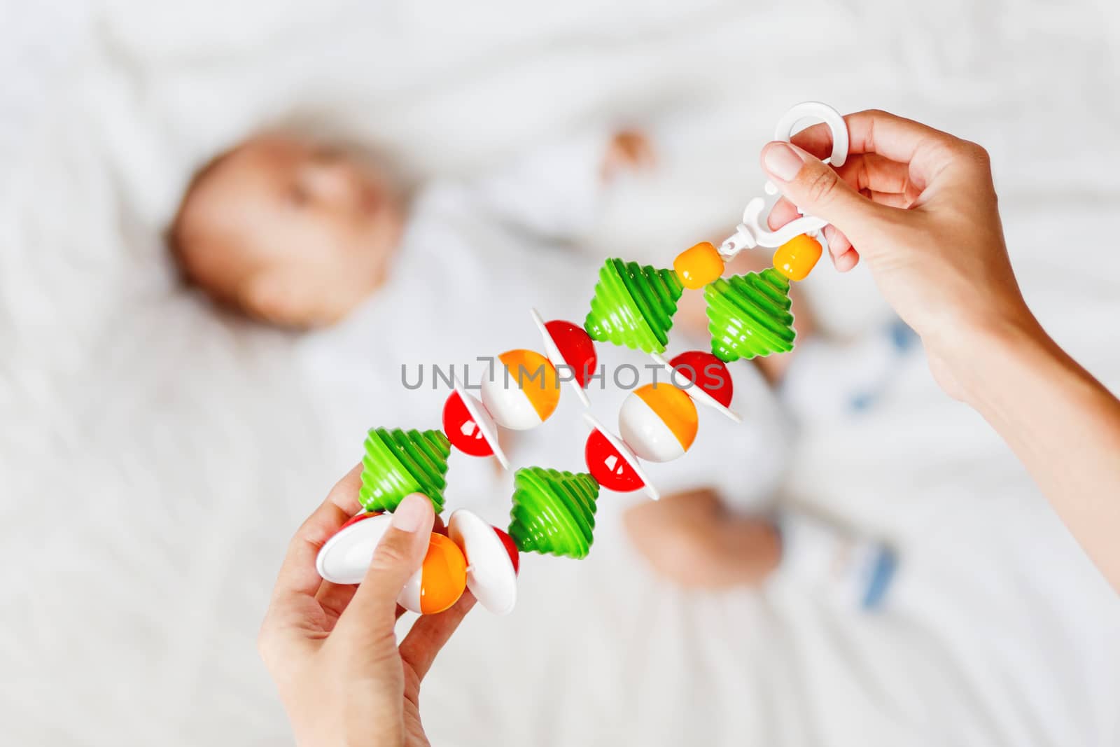 Woman holding baby's first toy - colorful rattle garland toy. Li by aksenovko