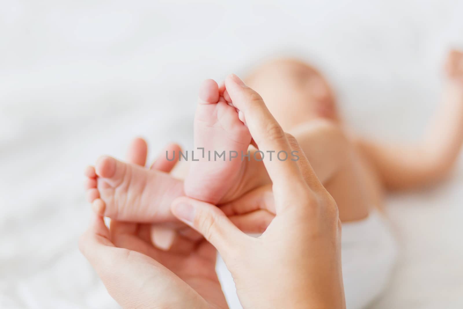 Mother holds newborn baby's bare feet. Tiny feet in woman's hand by aksenovko