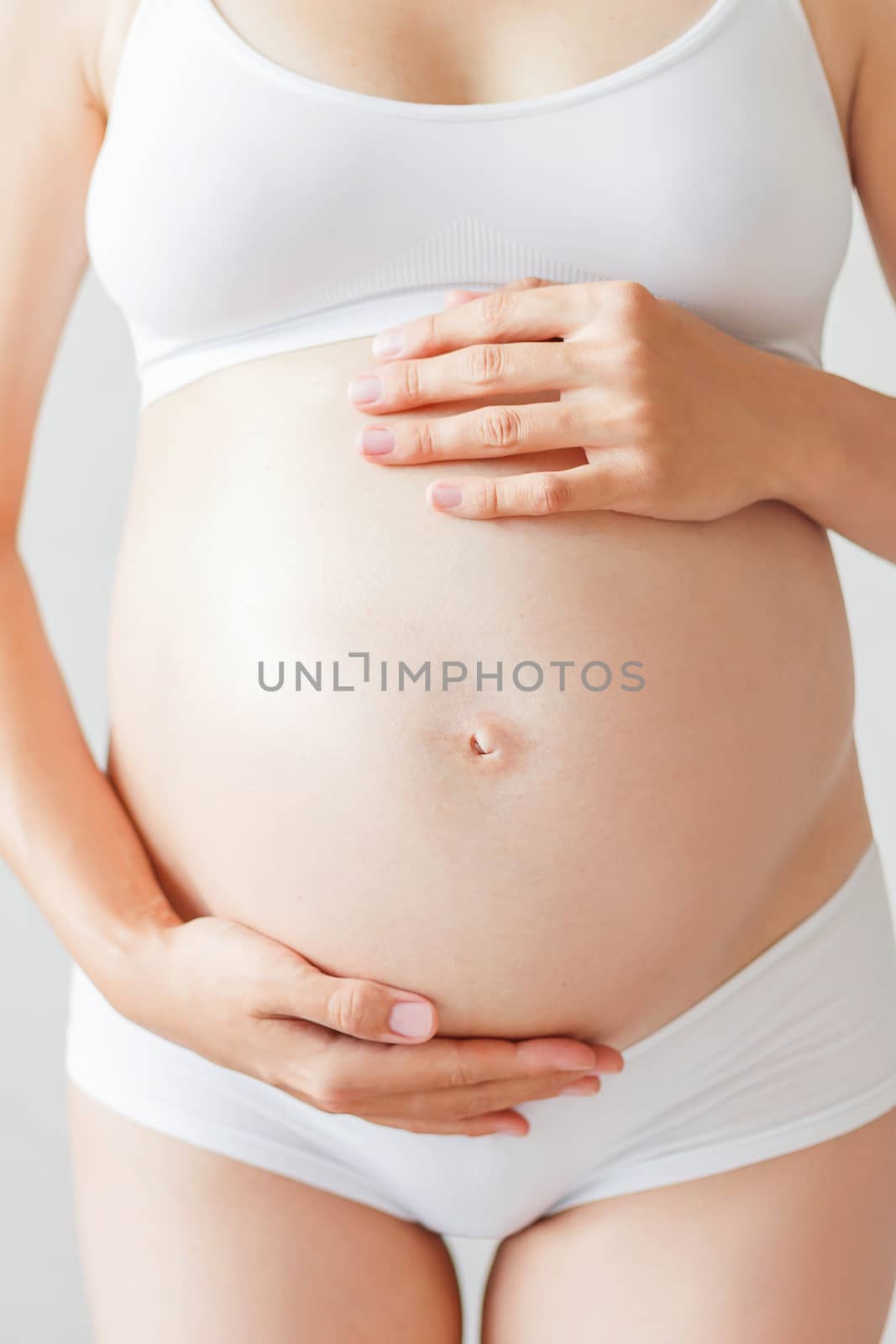 Pregnant woman in white underwear. Young woman expecting a baby.