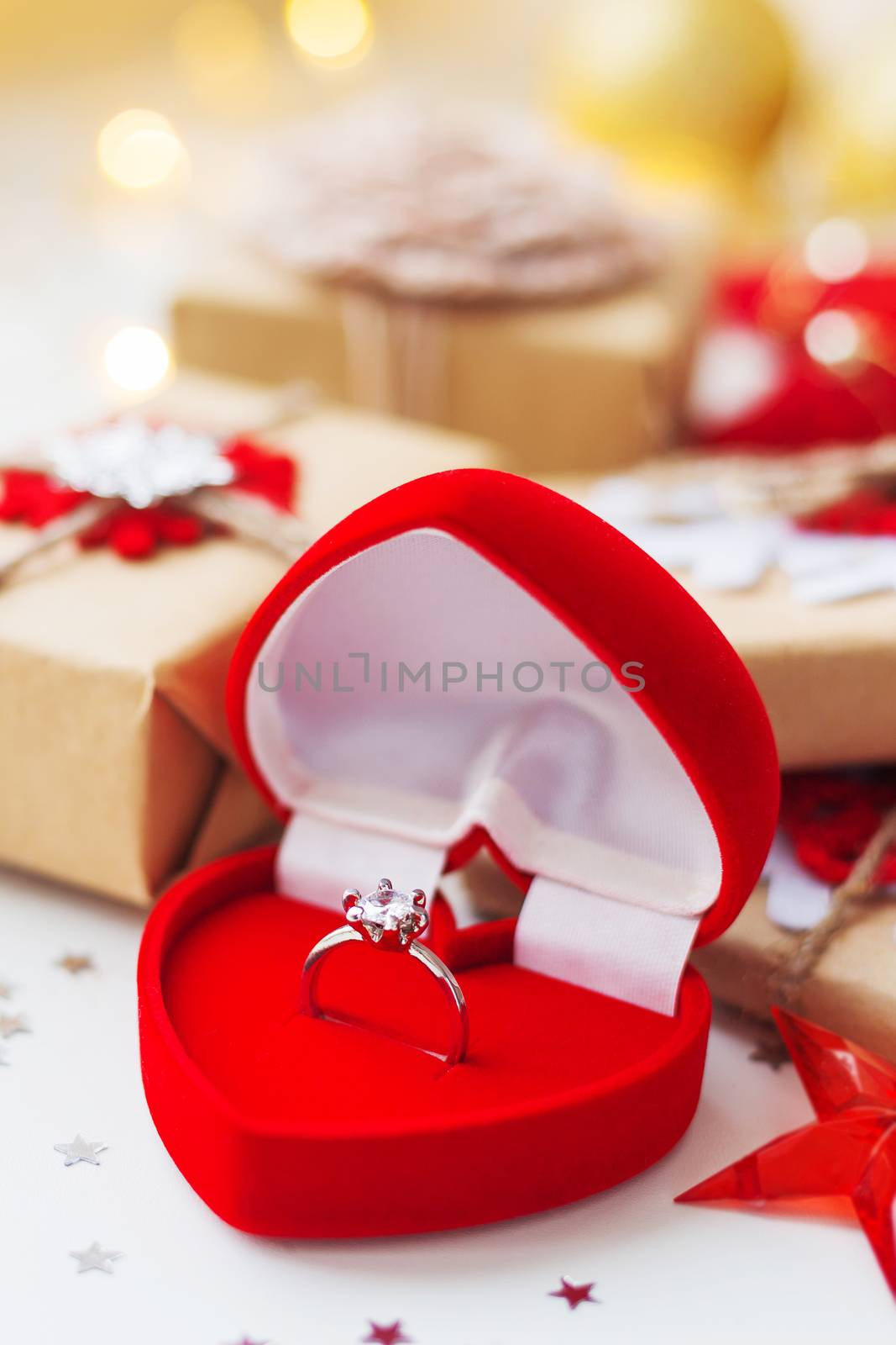 Christmas and New Year background with engagement ring and presents, decorations for Christmas tree. Holiday background with stars confetti and light bulbs.