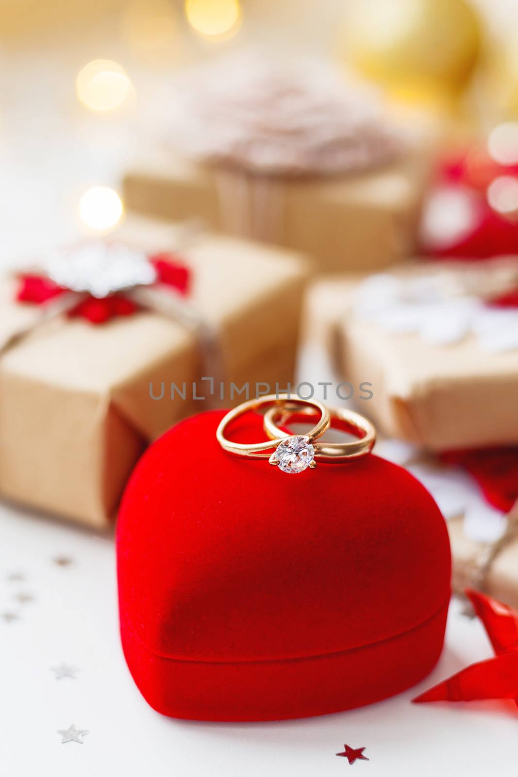 Christmas and New Year background with engagement rings and presents, decorations for Christmas tree. Holiday background with stars confetti and light bulbs. Place for text.