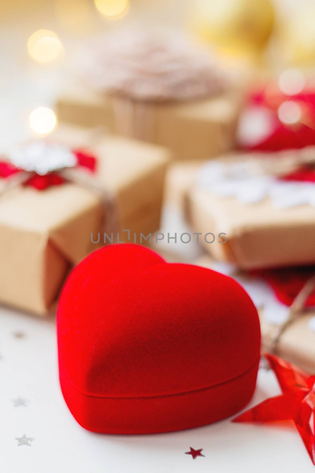 Christmas and New Year background with red box in shape of heart and presents, decorations for Christmas tree. Holiday background with stars confetti and light bulbs. Place for text.