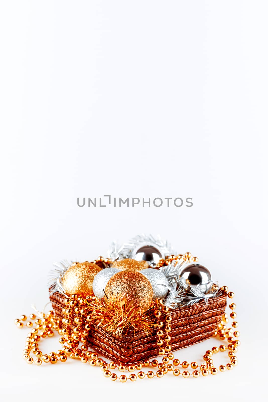 Golden and silver balls in box with tinsel and beads. Christmas and New Year decorations in woven box on white background. Copy space. by aksenovko