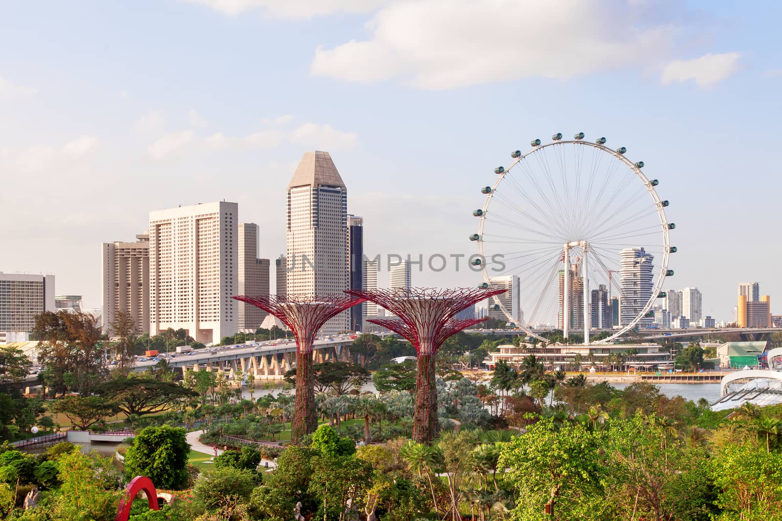 Singapore, panorama view - big wheel, hotel's buildings, Gandens at the Bay, road and bridge at sunset.