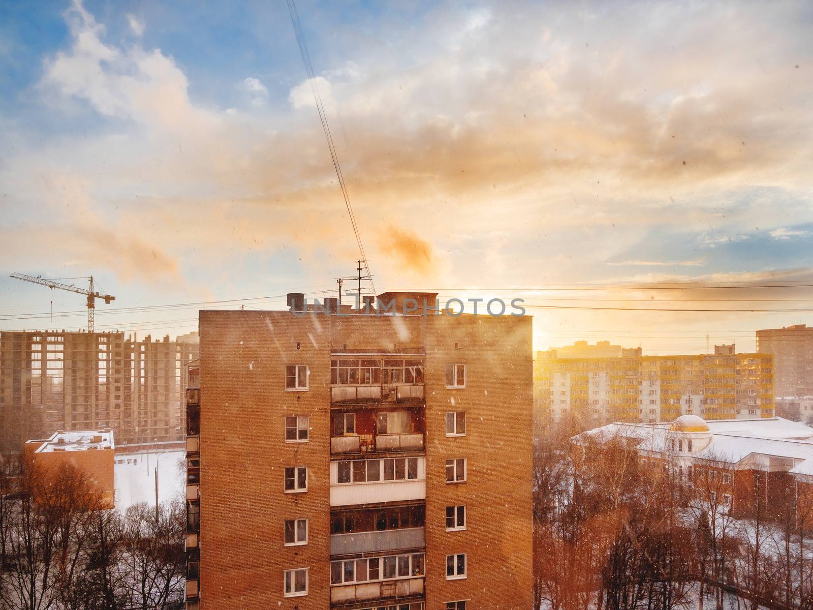 Winter sunset with snowfall. Cloudscape with sun rays upon Odintsovo town, Russia.
