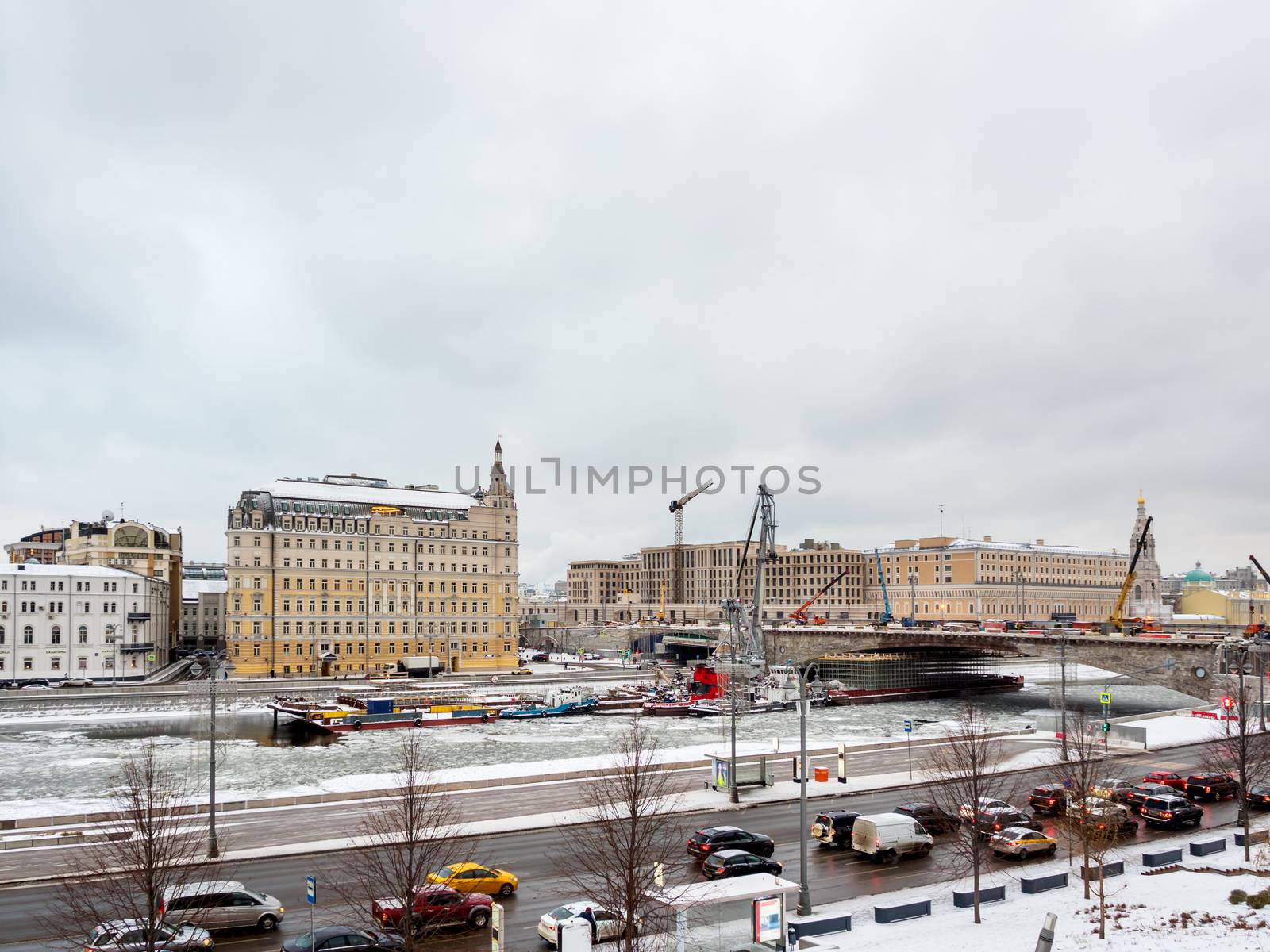 Ships with construction equipment are in Moscow-river under the bridge. Reconstruction of Bolshoy Moskvoretsky Bridge. Winter cloudy day in Moscow, Russia.