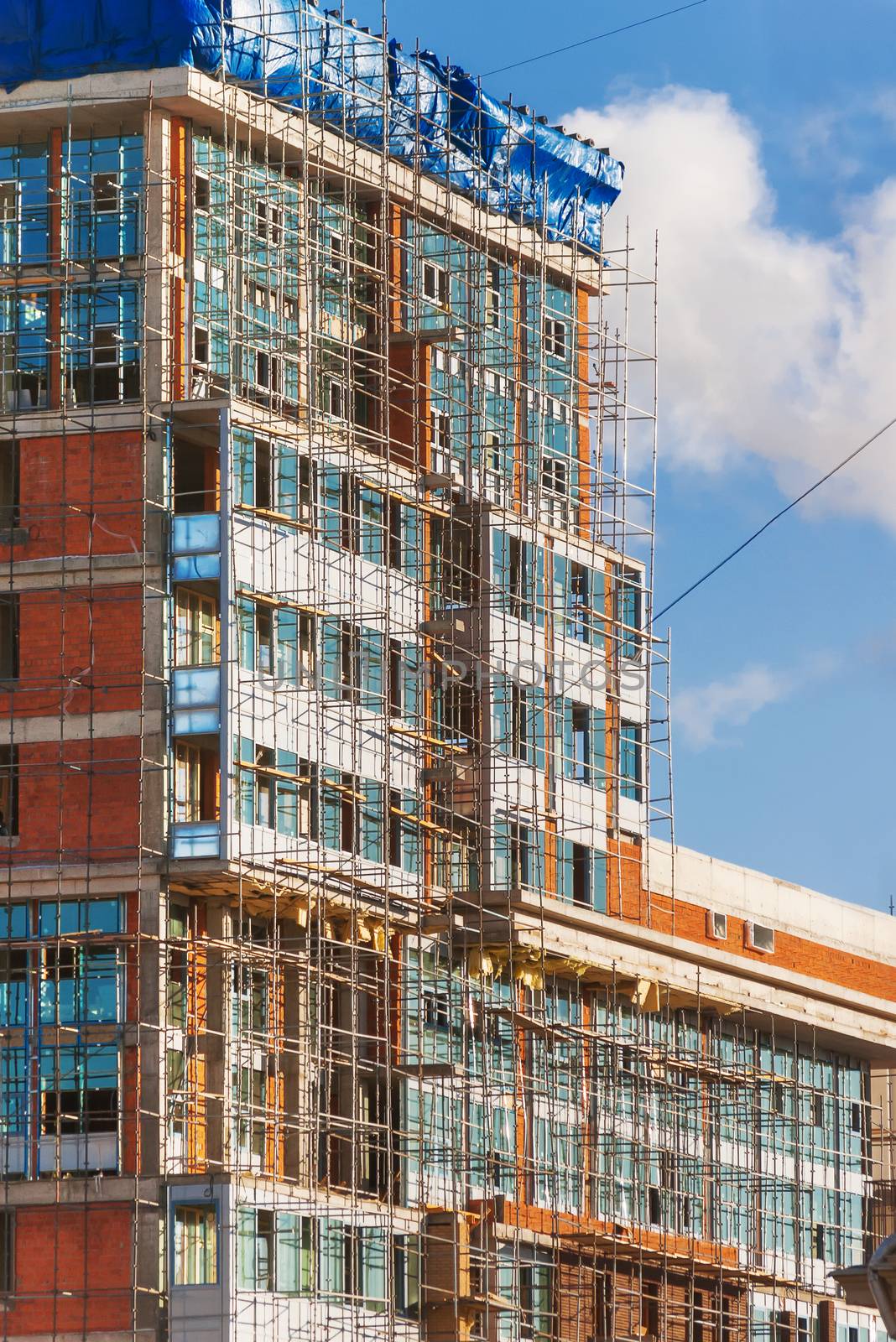 Construction of a building. A brick wall surrounded by scaffolding. by aksenovko