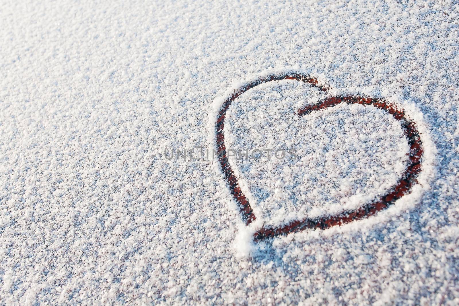 Heart drawn in snow. Symbol of love. Winter sunny day.