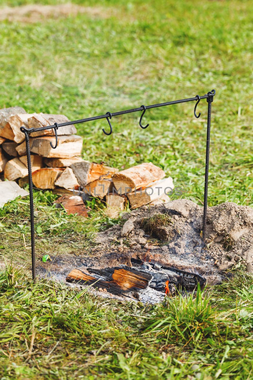 Fireplace with coals and holder for cauldron. Camping in forest.