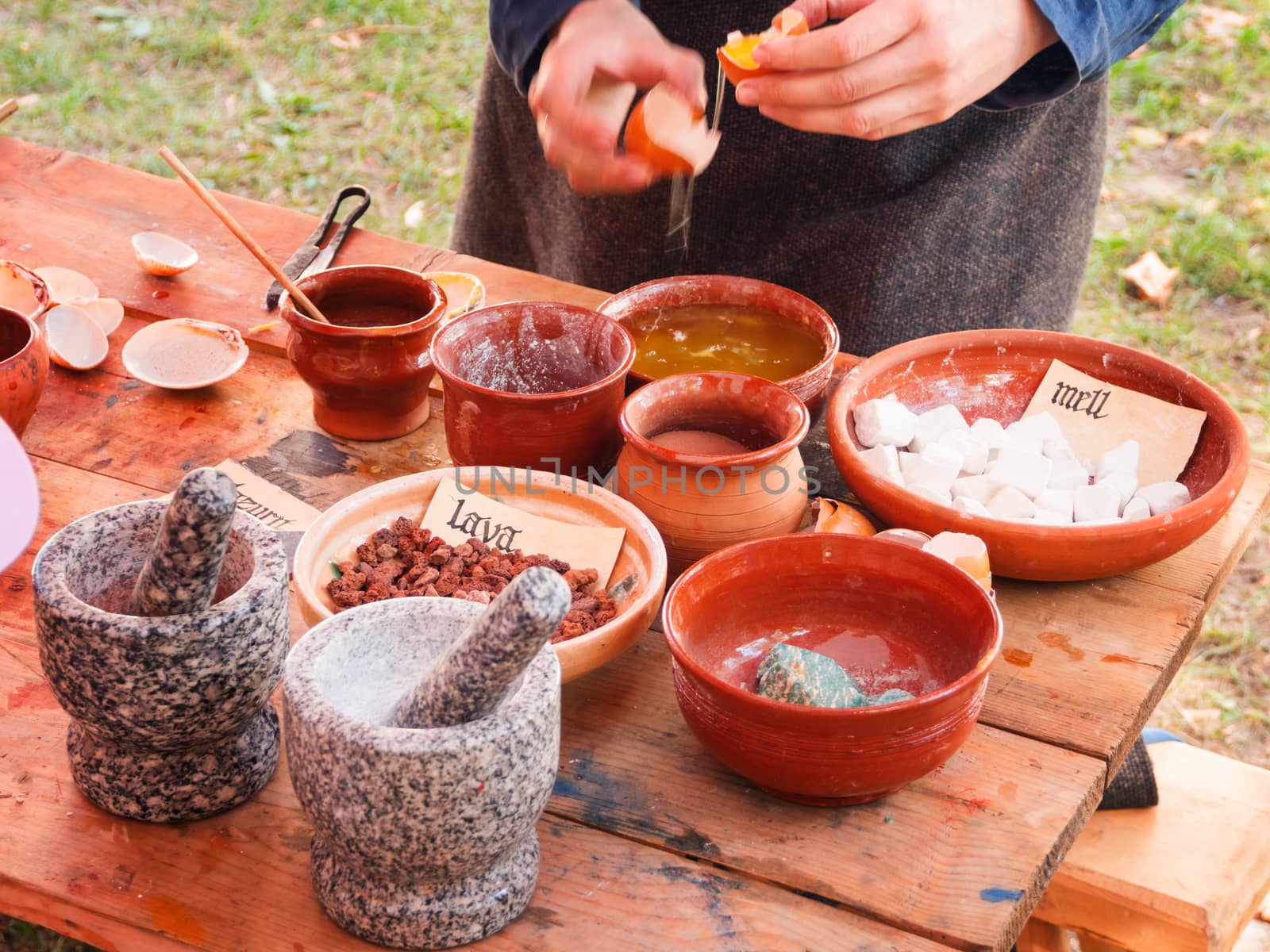 Woman dressed in medieval clothes making paints from natural ingredients. Annual festival Times and Epochs. Historical reconstruction of 19th century.