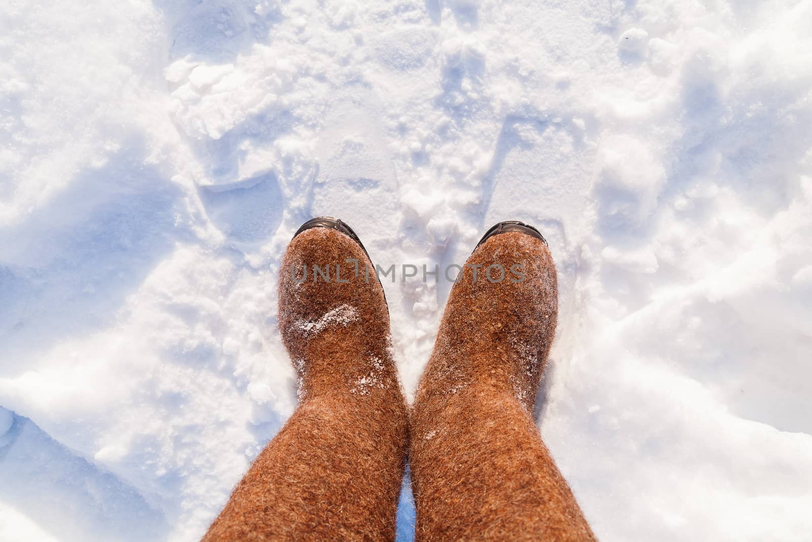 Russian traditional winter footwear - valenki. Winter sunny day, top view on feet felted wool boots.