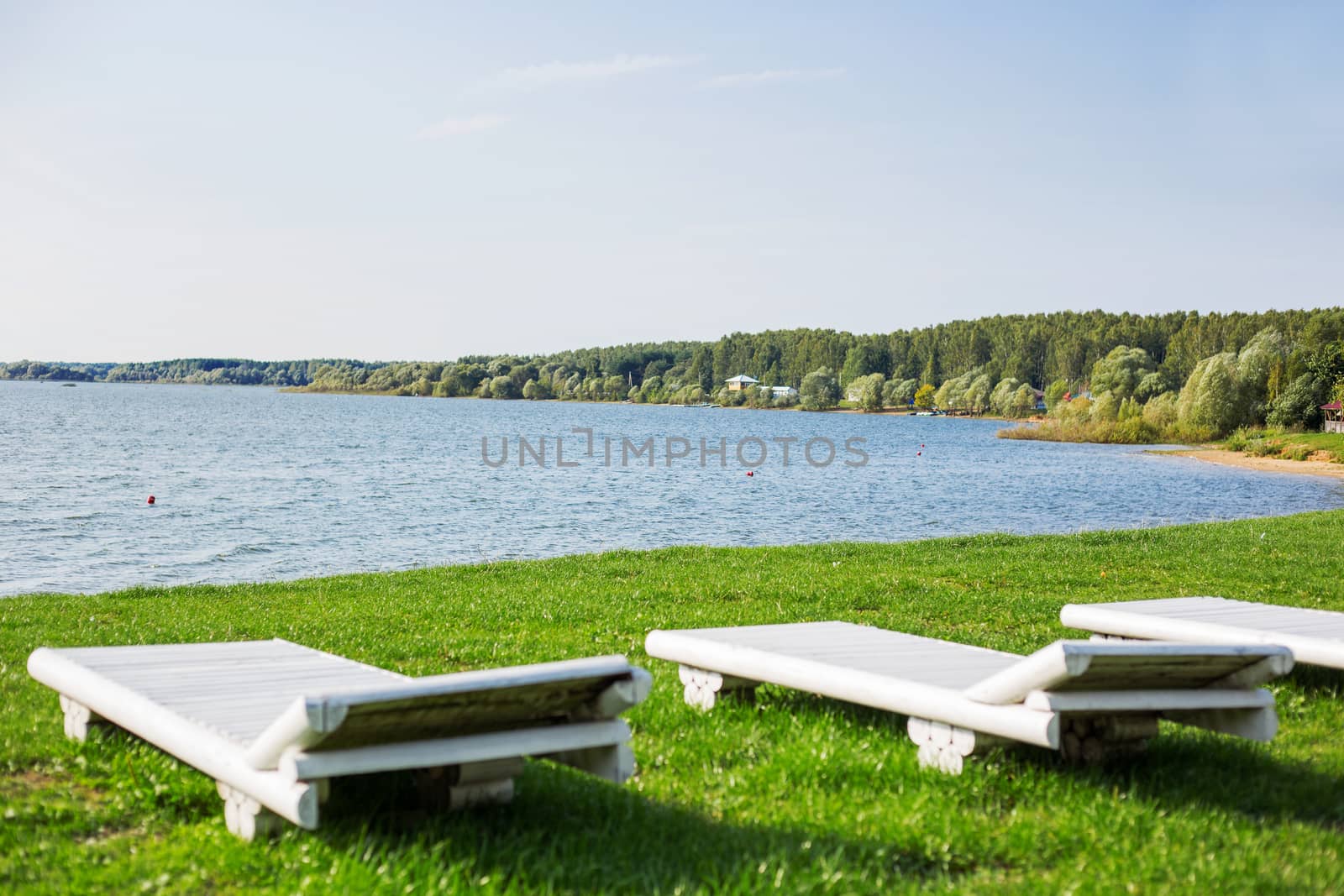 White wooden chaise lounges on the bank of the Ilyinsky reservoir. Outdoor recreation. Moscow region, Russia.