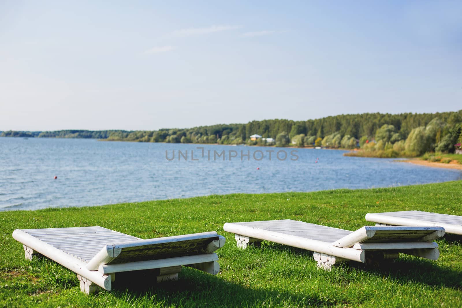 White wooden chaise lounges on the bank of the Ilyinsky reservoir. Outdoor recreation. Moscow region, Russia.