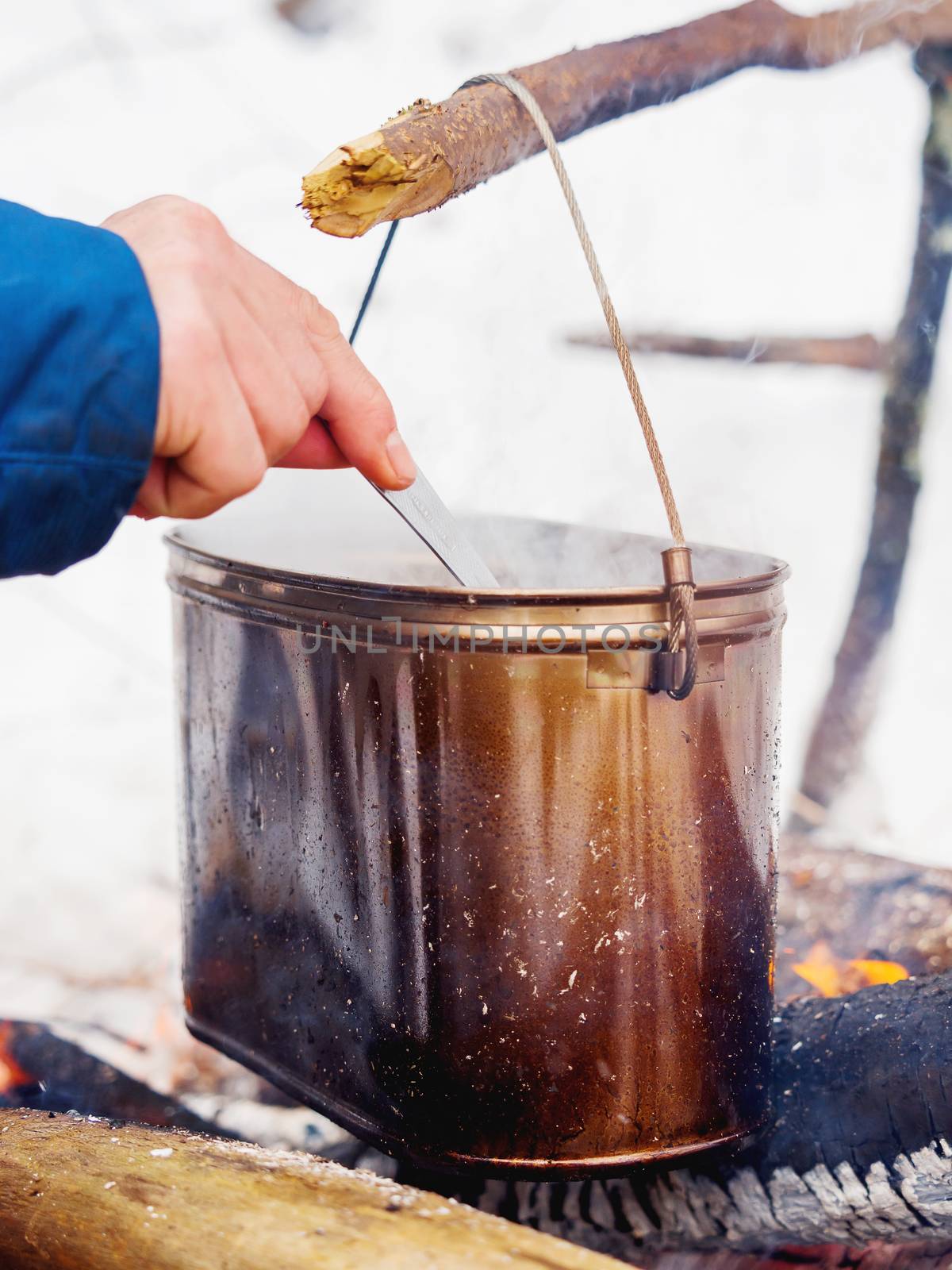 Cooking soup on a fire pot. Winter camping in forest.