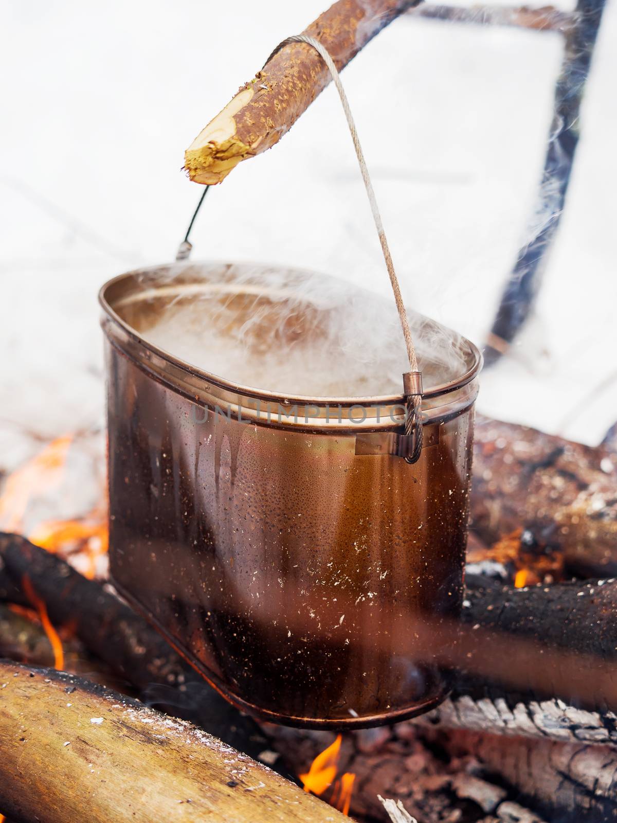 Cooking soup on a fire pot. Winter camping in forest. by aksenovko