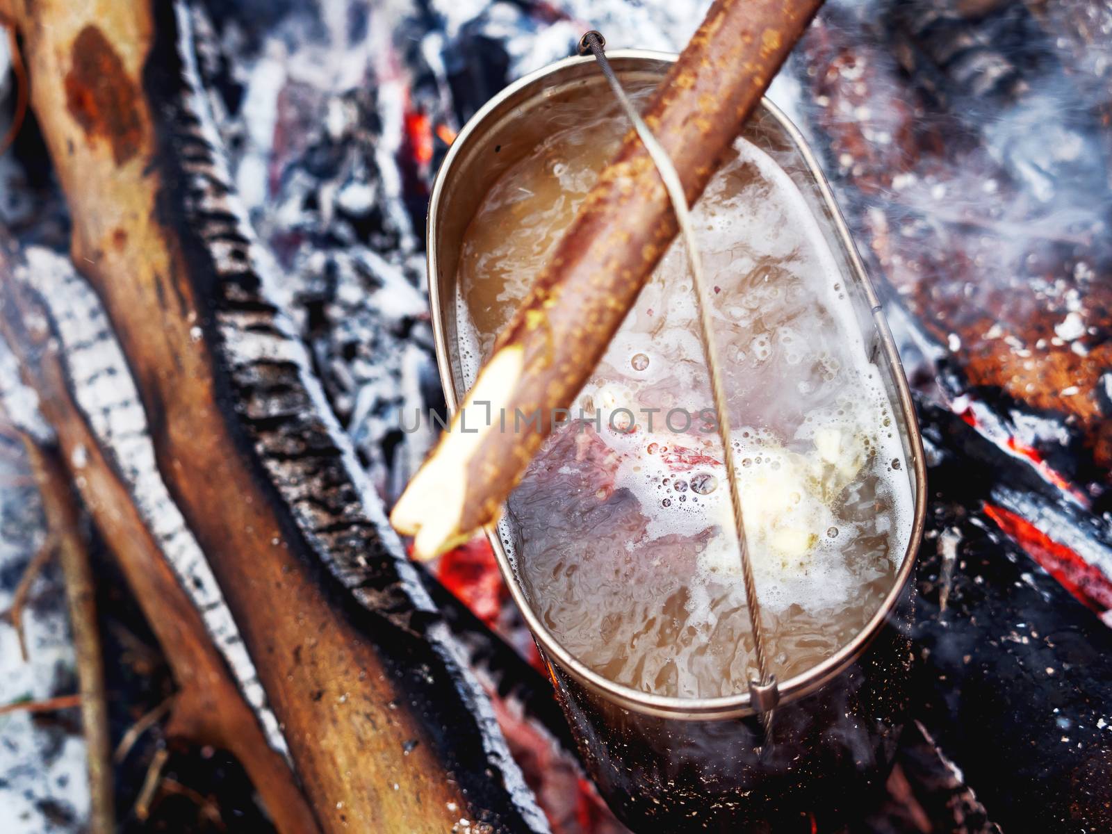 Cooking soup on a fire pot. Winter camping in forest.