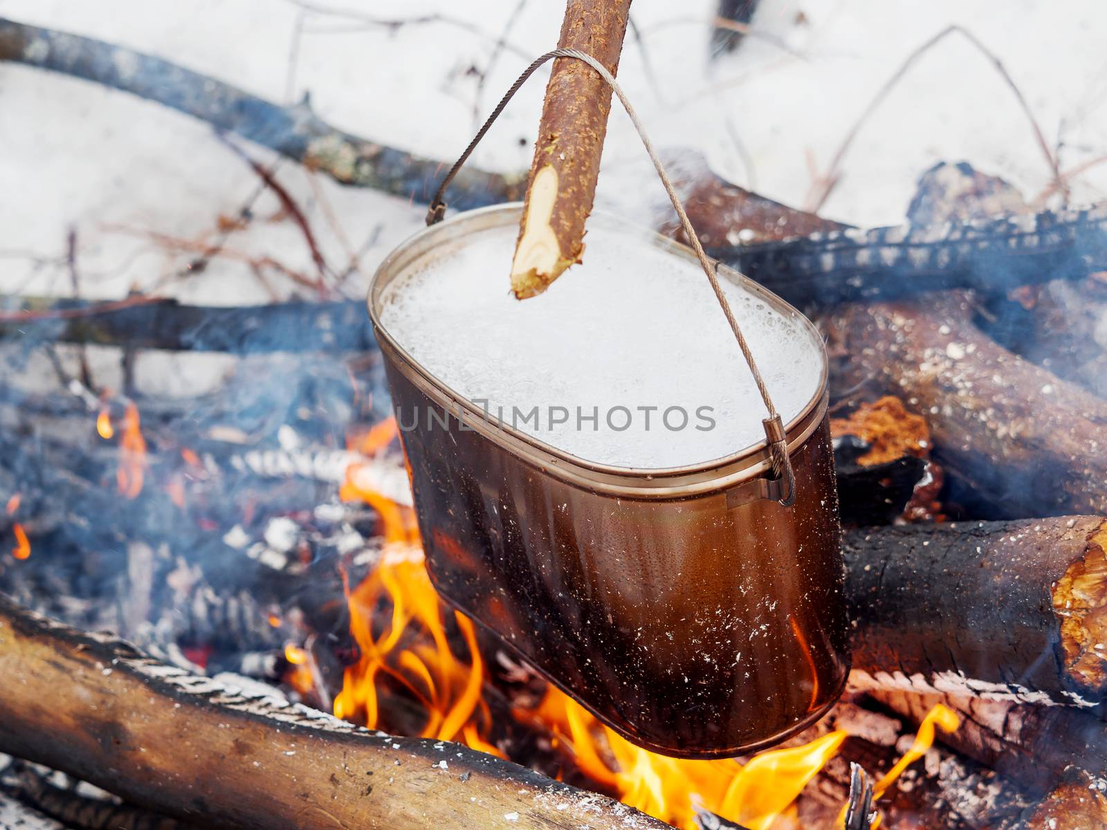 Cooking soup on a fire pot. Winter camping in forest.