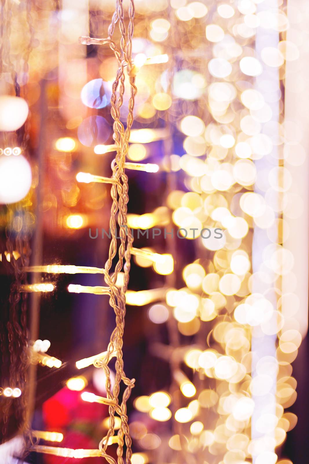 Defocused night street lights, blurred colorful bokeh background. Holiday colorful lanterns and light bulbs garlands.