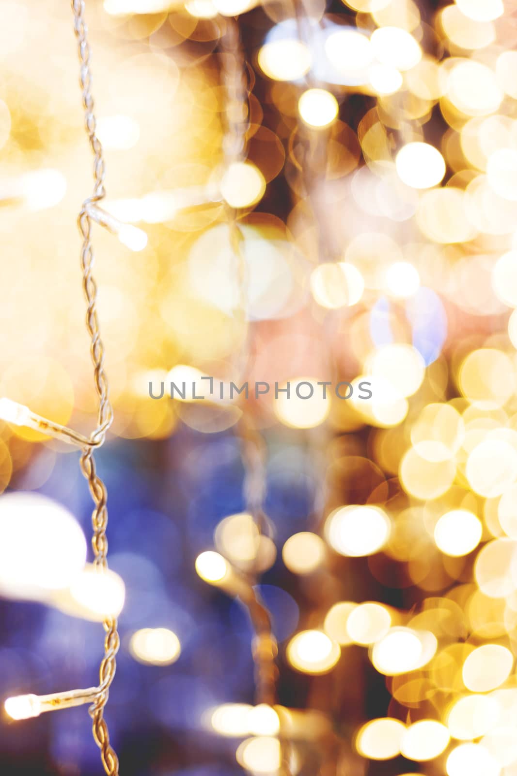 Defocused night street lights, blurred colorful bokeh background. Holiday colorful lanterns and light bulbs garlands.