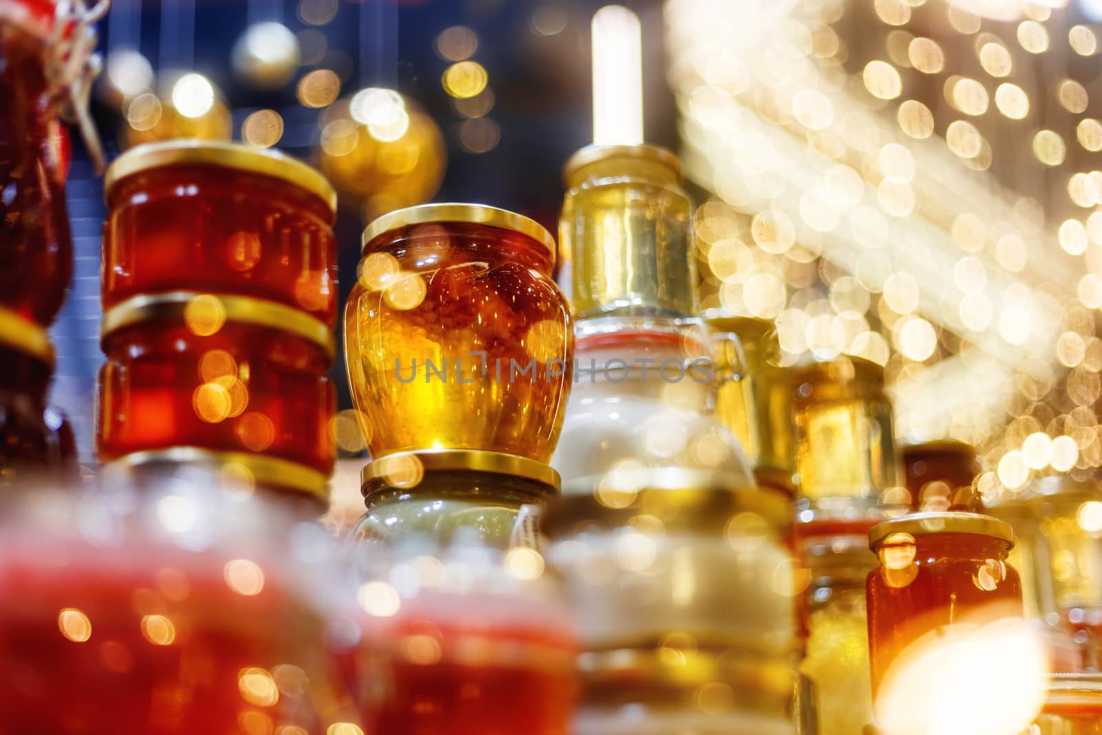 Holiday fair. Jars of honey glowing in garlands of lighting bulbs.