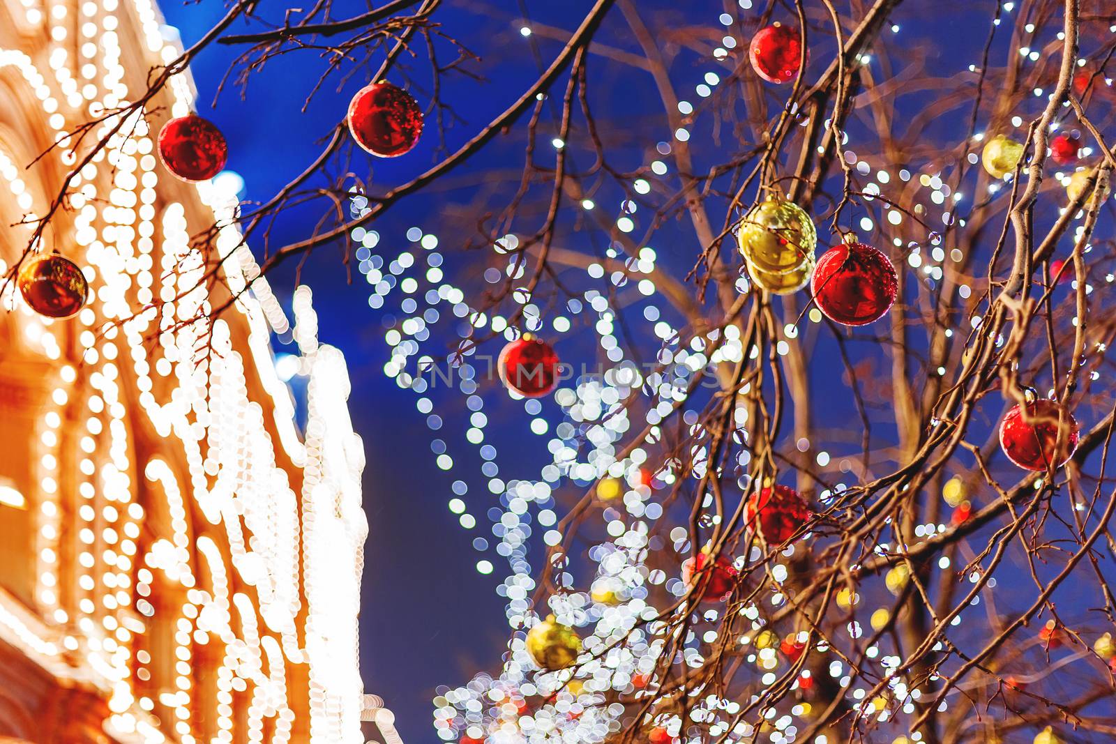 Streets of Moscow decorated for New Year and Christmas celebration. Tree with bright red and yellow balls. GUM (Main Department Store) building with light bulbs. Russia.