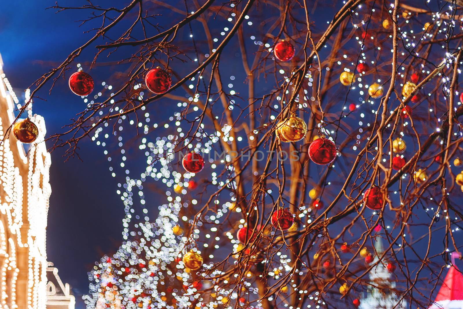 Streets of Moscow decorated for New Year and Christmas celebration. Tree with bright red and yellow balls. GUM (Main Department Store) building with light bulbs. Russia.