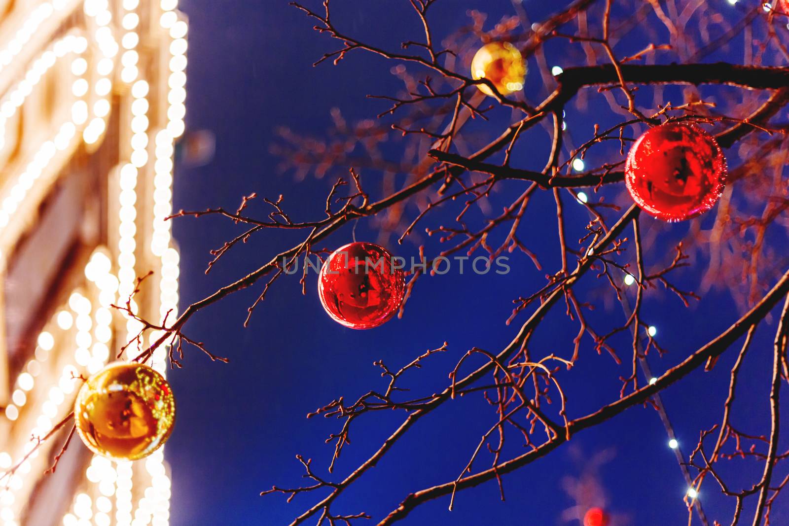 Streets of Moscow decorated for New Year and Christmas celebration. Tree with bright red and yellow balls. GUM (Main Department Store) with light bulbs on background. Russia.