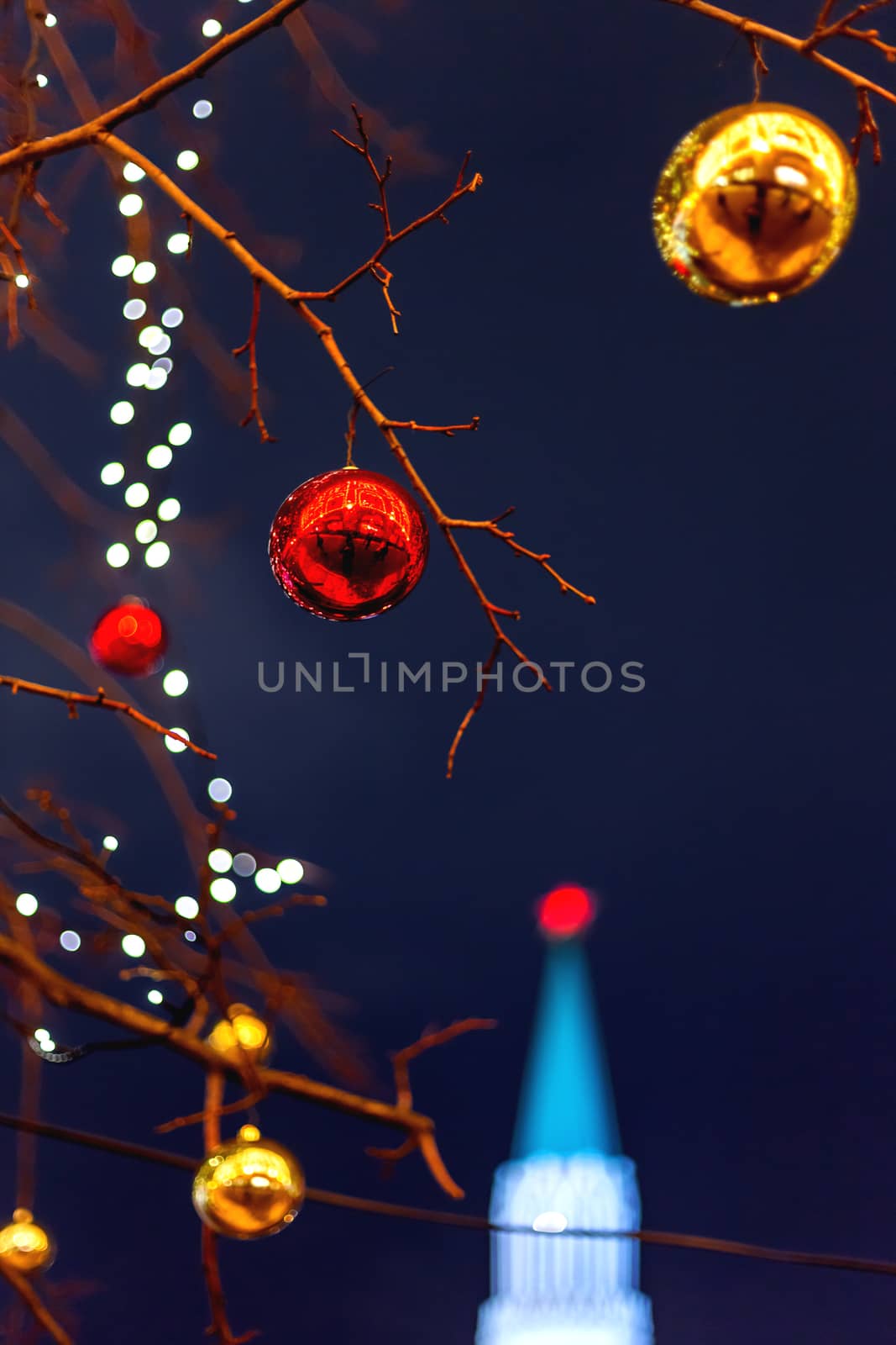 Streets of Moscow decorated for New Year and Christmas celebration. Tree with bright red and yellow balls. The St.Nicholas (Nikolskaya) tower of Kremlin on the background. Russia. by aksenovko